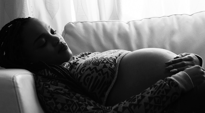 Sad pregnant woman lying on a couch