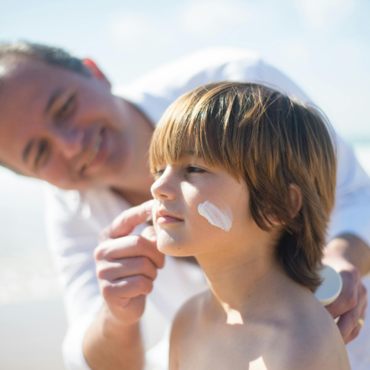  Parent applying sunscreen to child’s cheeks at the beach 